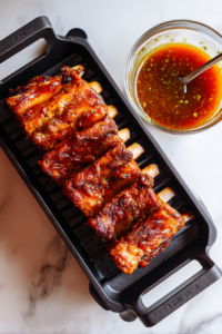 smoking-ribs-brushed-with-sauce-in-black-rack-on-white-marble