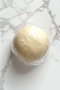 soft-biscuit-dough-wrapped-in-cling-film-on-white-marble-for-chilling