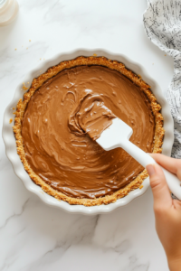 spreading-first-layer-of-nutella-onto-graham-cracker-crust-top-down