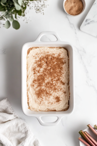 sprinkling-cinnamon-sugar-on-rhubarb-cake-in-filled-handle-dish