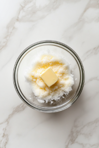 sugar-and-softened-butter-in-glass-bowl-for-streusel-on-white-marble