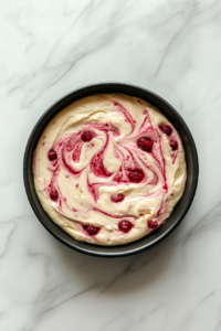 swirled-cake-batter-with-compote-in-black-round-pan