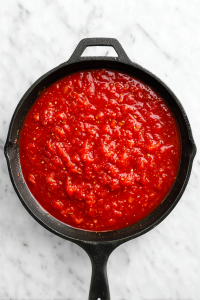 tomato-puree-and-tomatoes-in-black-skillet-on-marble