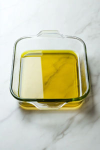 top-down-coating-baking-dish-with-olive-oil-on-white-marble-cooktop