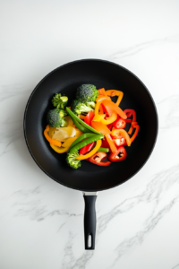 top-down-colorful-veggies-in-black-skillet-on-white-marble-keto-stirfry