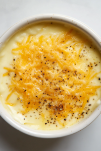 top-down-seasoning-cheese-sauce-with-salt-and-pepper-in-black-dutch-oven