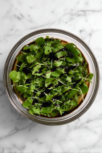 tossing-arugula-with-balsamic-in-glass-bowl-on-white-marble