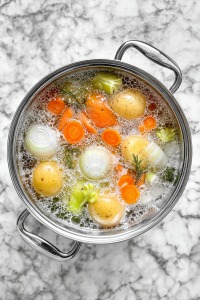 water-added-to-glass-pot-with-vegetables-on-white-marble