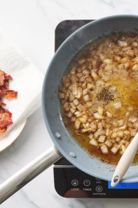 Add the chopped onion to the hot bacon